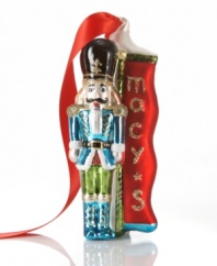 Macy's Soldier ornament stands by to protect presents from overeager children. He poses beside the store's holiday banner in brilliant red, blue and green glass.