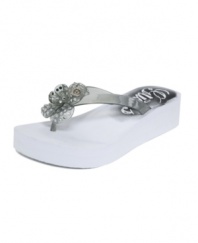 Summer loving. A sparkling flower and cute logo charm spice up the Ebba wedge thong sandals by GUESS.