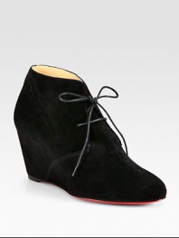 Trend-forward suede ankle boot has a lace-up front, self-covered wedge and signature red leather sole. Self-covered wedge, 3 (75mm)Suede upperLeather liningSignature red leather solePadded insoleMade in ItalyOUR FIT MODEL RECOMMENDS ordering one half size up as this style runs small. 